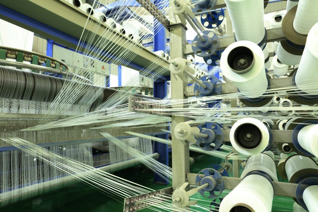 Smart Weaving for Sustainable Fabrics | D&J Fashion OEM & ODM Automated weaving machines in a textile factory producing sustainable fabrics, demonstrating D&J Fashion’s AI-powered zero-waste manufacturing solutions.
