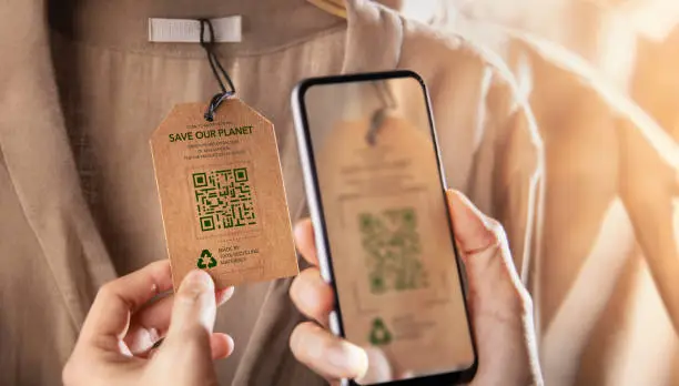 Blockchain Traceability in Sustainable Apparel | D&J Fashion Consumer scanning a QR code tag on a sustainable garment, emphasizing D&J Fashion’s blockchain-backed traceability in ethical fashion manufacturing.