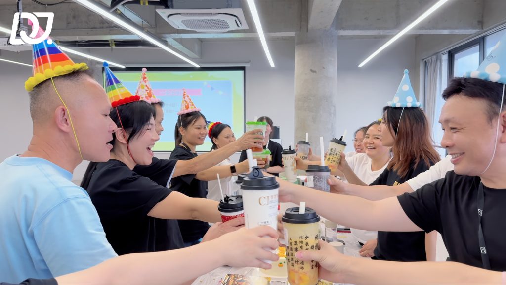 D&J Fashion Group employees wearing birthday hats making a cheerful toast together during the September birthday celebration